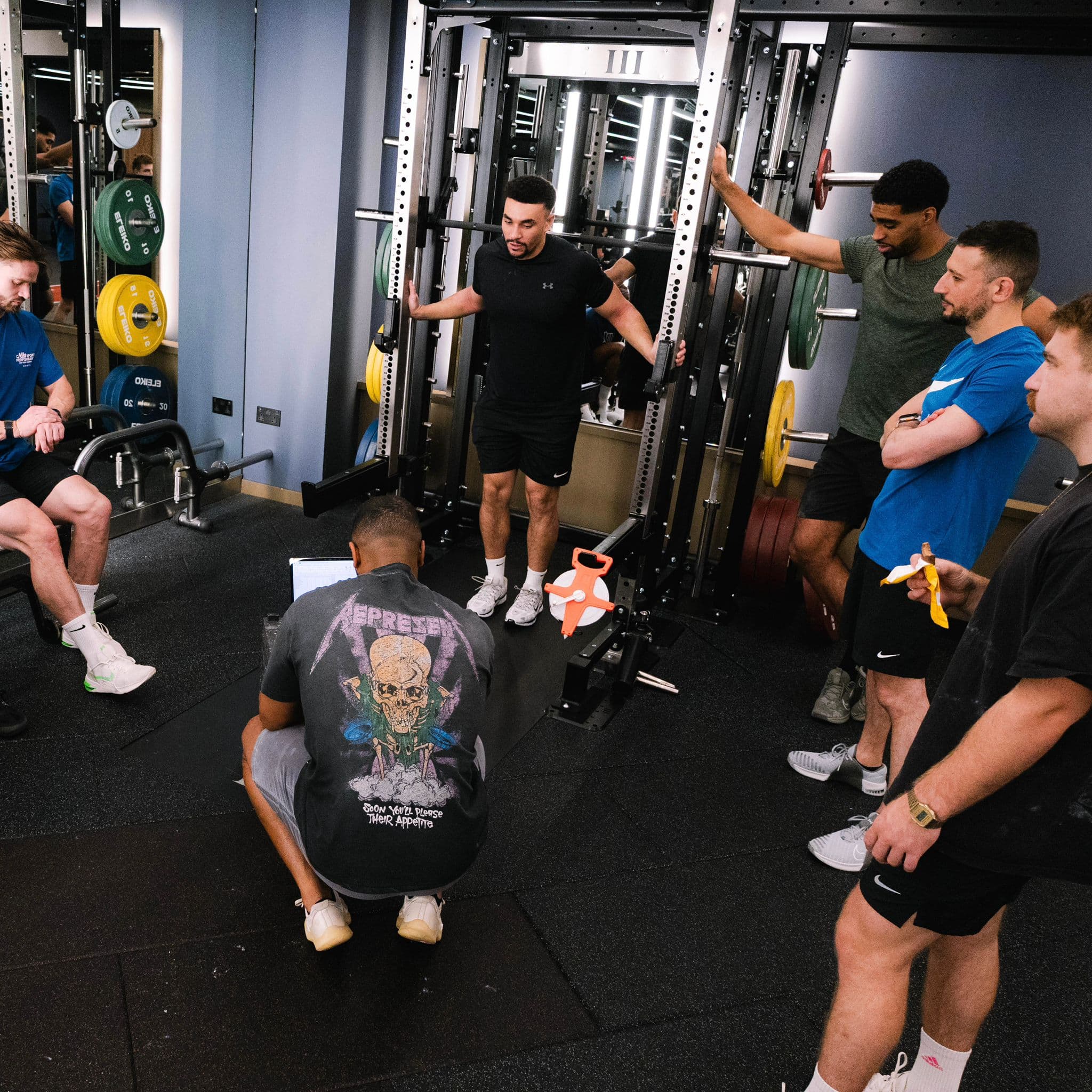 Coach mentoring a group at the squat rack